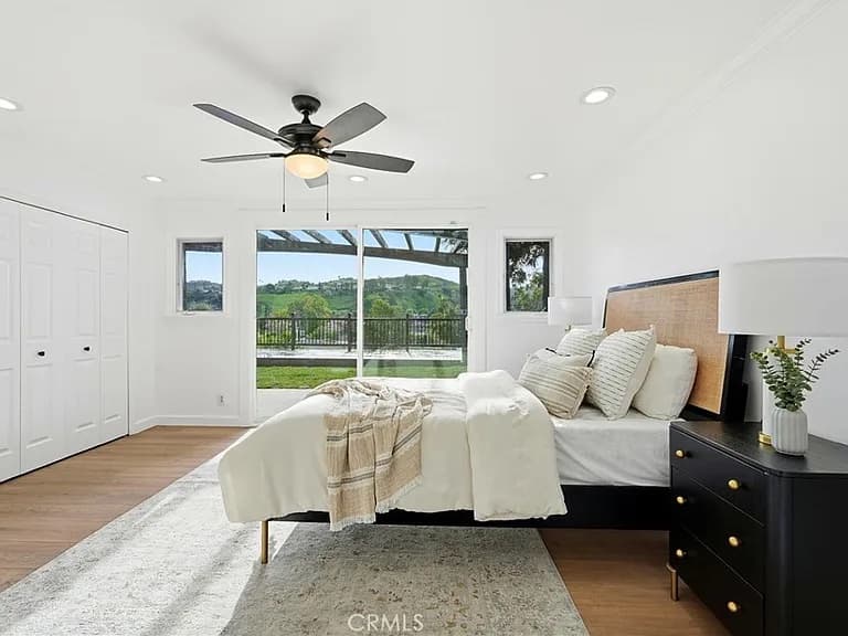 Primary bedroom with a ceiling fan and sliding doors opening to a hillside view