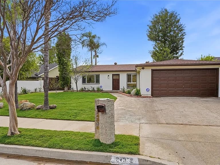 Single-story ranch home with a brown two-car garage and mature front lawn on Highlander Road in West Hills