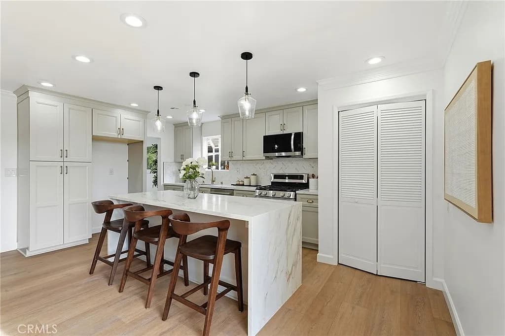 Remodelled kitchen with a waterfall quartz island, pendant lighting and stainless range