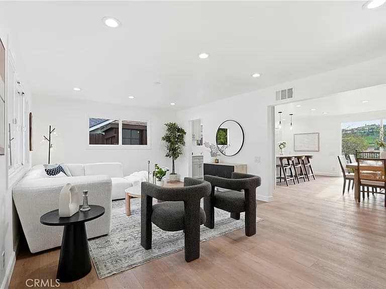 Open living room with light wood floors looking through to the dining area and kitchen